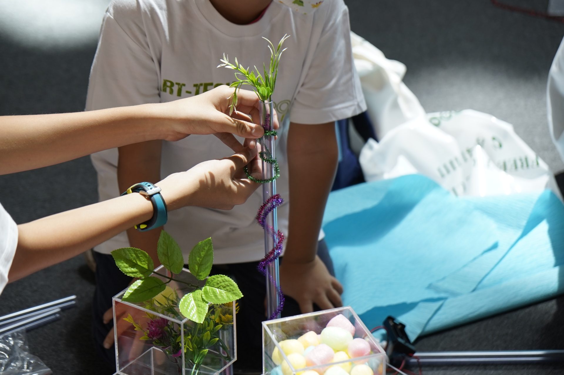 Children's hands assembling a plant installation piece by piece